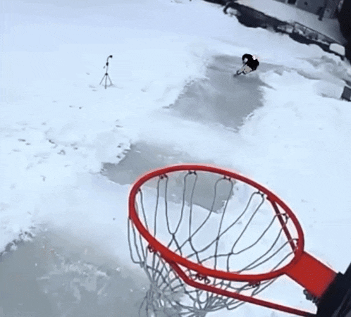 a person playing basketball in the snow with a basketball in the net