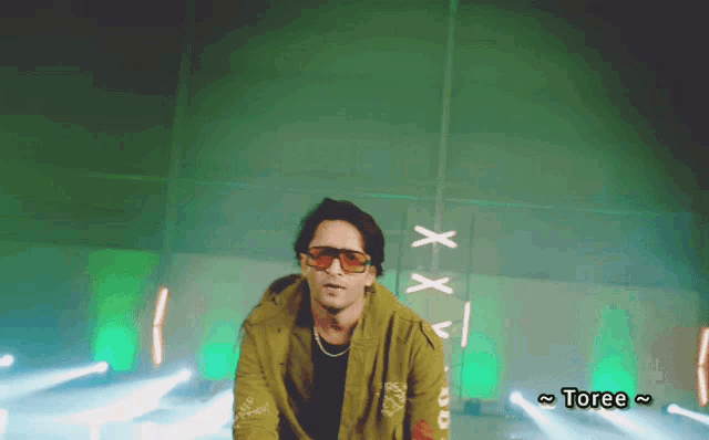 a man wearing sunglasses and a yellow jacket with the word toree on the bottom right