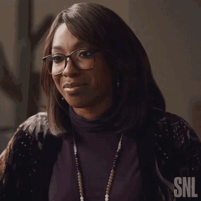 a woman wearing glasses and a purple shirt with snl written on the bottom right
