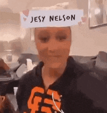 a woman is wearing a paper hat that says jesy nelson on it .