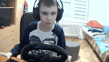 a boy wearing headphones holds a steering wheel in front of him
