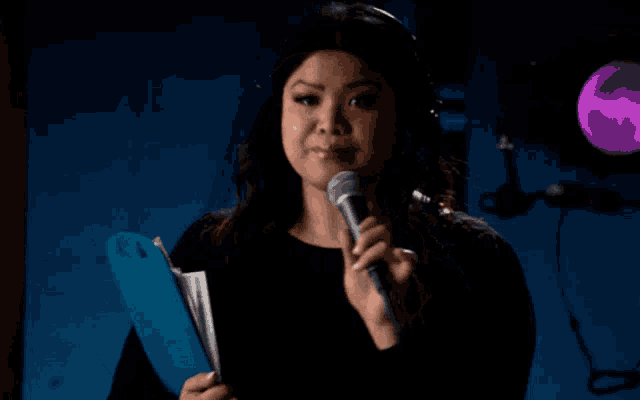 a woman wearing headphones is holding a clipboard and a microphone and saying thank you