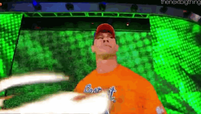 a man in an orange shirt is standing in front of a green background ..