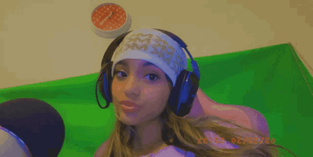 a girl wearing headphones and a headband has a clock on the wall above her head