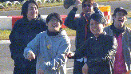 a group of young men are standing next to each other on a road and smiling .