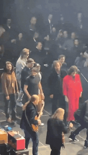 a woman in a red dress is walking on a stage
