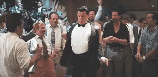 a man in a tuxedo is dancing in a crowd