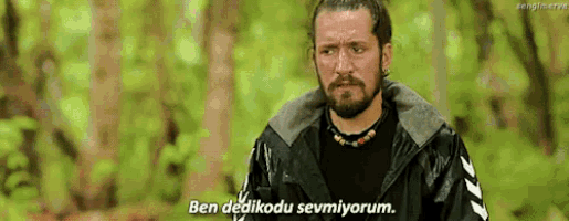 a man with a beard is standing in the woods and says ben dedikodu sevmiyorum
