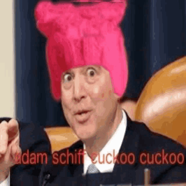 a man wearing a pink hat is sitting in a chair and pointing at the camera .