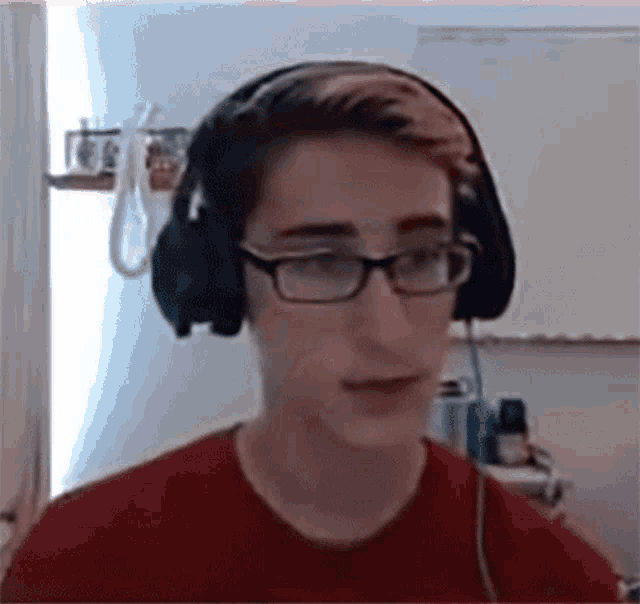 a young man wearing headphones and glasses looks at the camera .