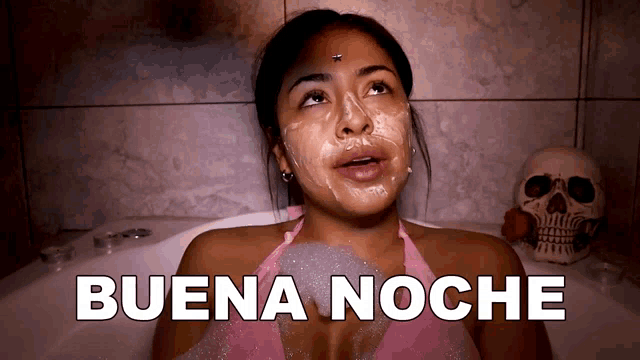 a woman is laying in a bathtub with foam on her face and the words buena noche below her