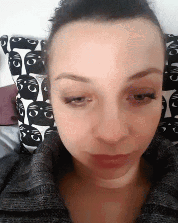 a close up of a woman 's face with a cat patterned pillow in the background