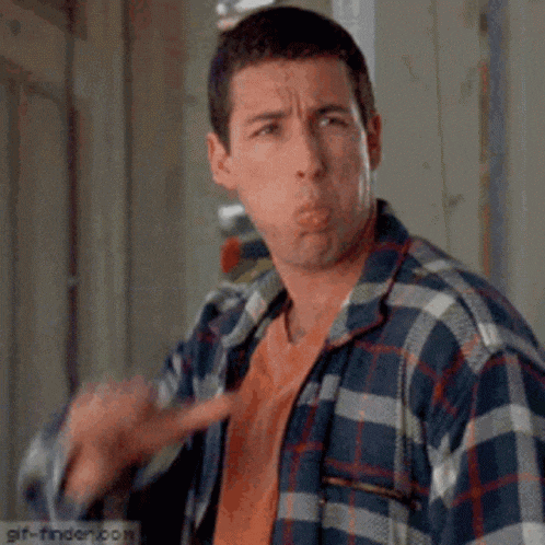a man in a plaid shirt is making a funny face while pointing at the camera .