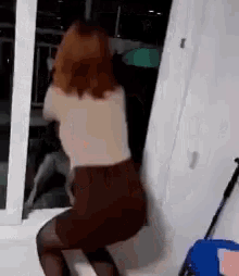 a woman in a brown skirt is squatting down in front of a sliding glass door .
