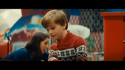 a boy in a red sweater is playing with a girl in a blue dress in a room .