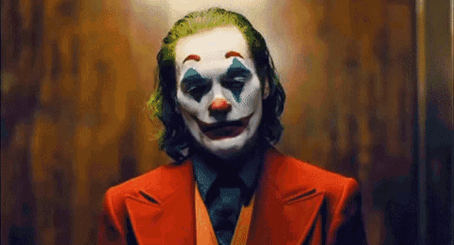 a close up of a man dressed as the joker in a red suit and tie .