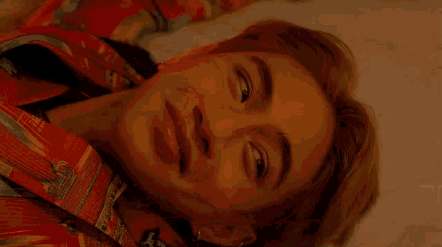 a close up of a person 's face with a red jacket that says ' x ' on it