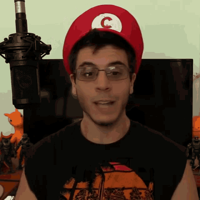 a man wearing glasses and a red hat with a white letter c on it