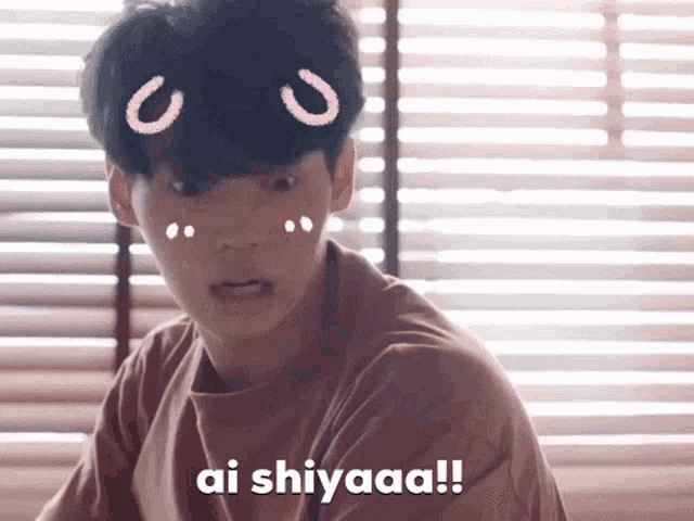 a young man is sitting in front of a window and says ai shiaaa