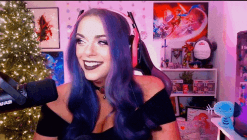 a woman with purple hair is smiling in front of a microphone while wearing headphones .