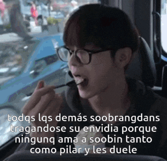 a man wearing glasses is eating something with chopsticks