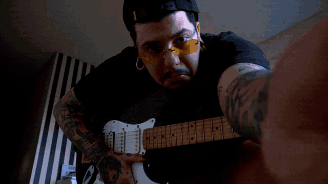 a man with a tattoo on his arm playing a guitar