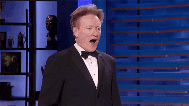 a man in a tuxedo and bow tie looks surprised
