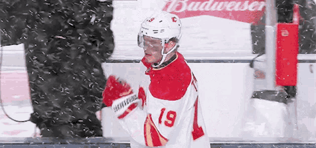 a hockey player wearing a number 19 jersey stands in the snow