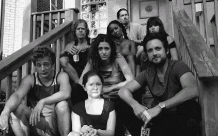 a black and white photo of a group of people sitting on the steps of a building .