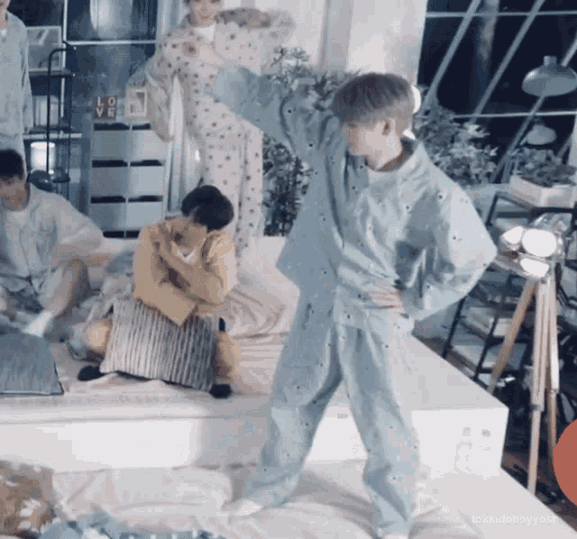 a man in pajamas is standing on a bed with his hand on his hip