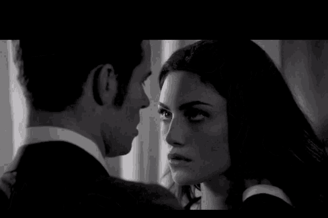 a man in a suit and tie kisses a woman in a black and white photo
