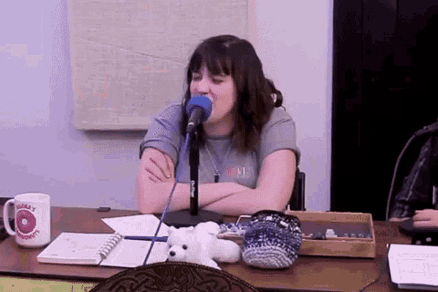 a woman sitting in front of a microphone with a mug that says today