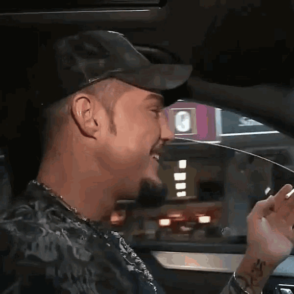 a man in a hat is sitting in the driver 's seat of a car .