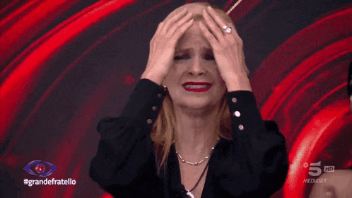 a woman is crying in front of a red background that says grandefratello on it