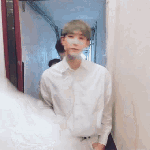a man in a white shirt is standing in a hallway looking at the camera .