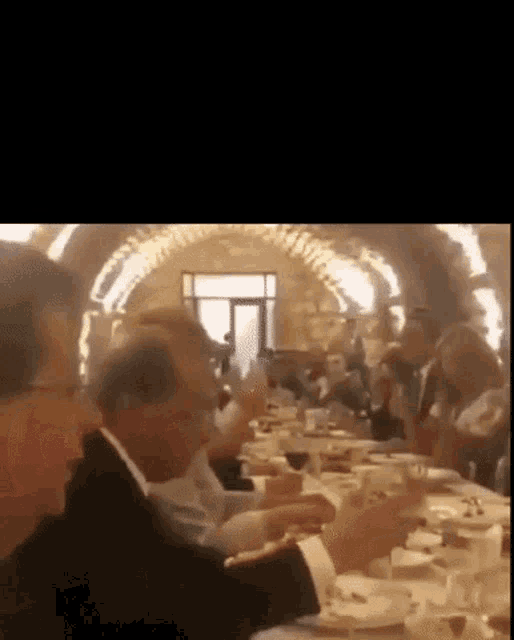 a group of people are sitting at a long table in a restaurant eating food .