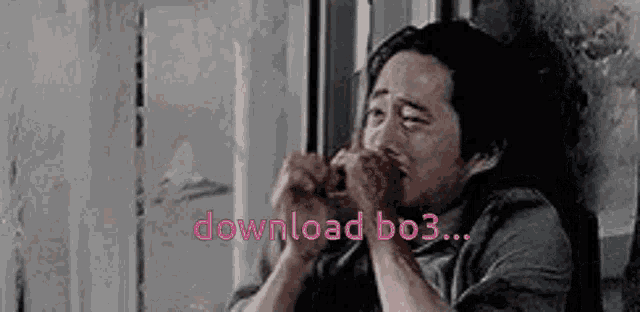 a man is sitting in front of a window with his hands on his face and the words download bo3 written in pink .