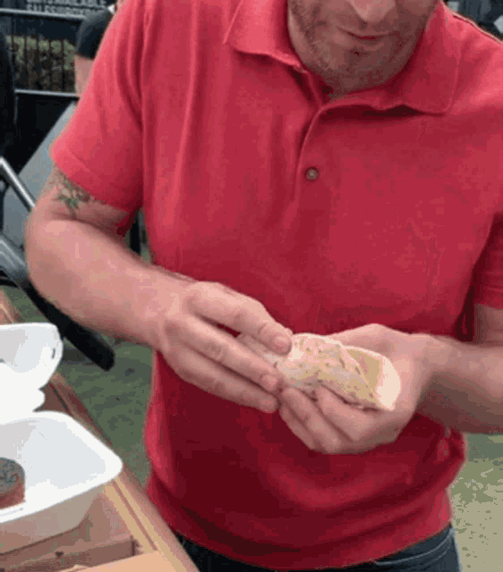a man in a red shirt is holding a piece of food in his hand