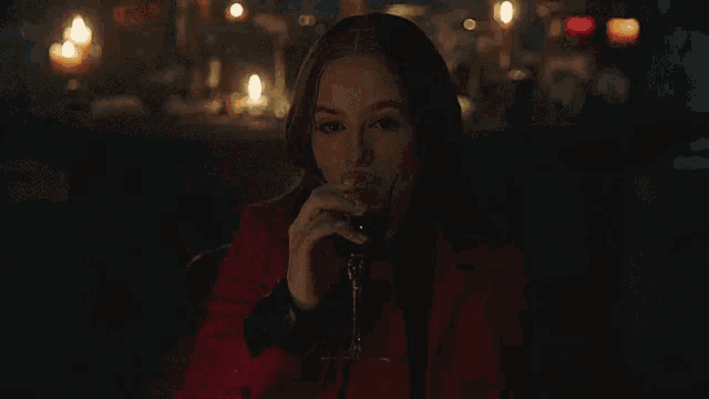 a woman in a red coat is holding a glass of wine in her hand .