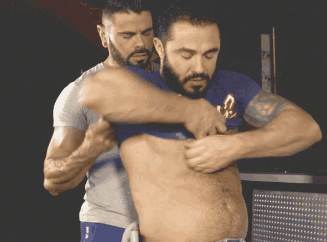 a man in a blue shirt with the letter c on it is being helped by another man