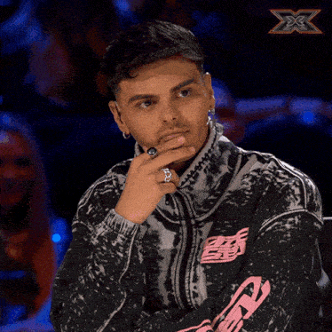 a man with a ring on his finger is wearing a tie dye jacket with the word x on it