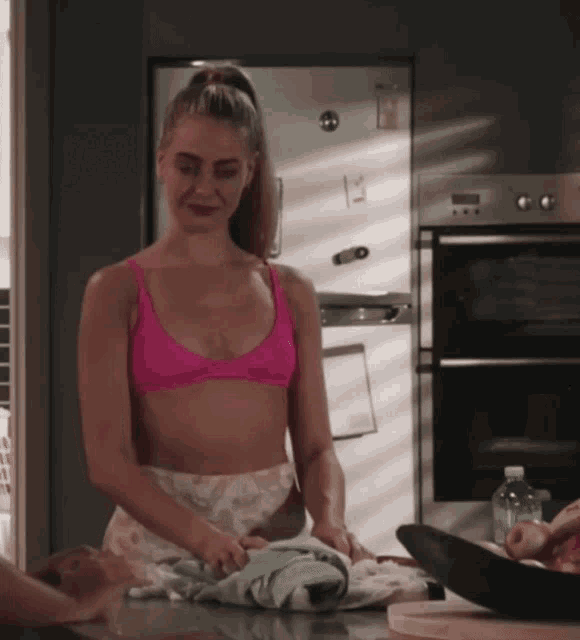 a woman in a pink bikini top is standing on a counter