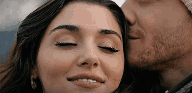 a man is kissing a woman on the cheek while she smiles .