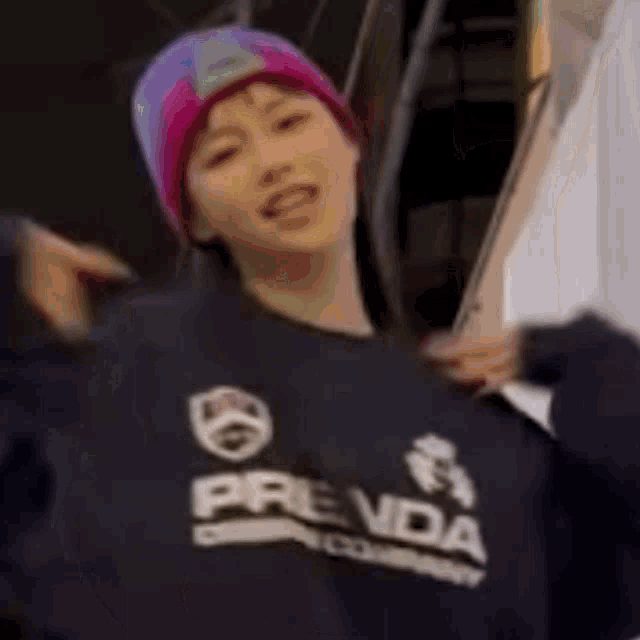 a young girl wearing a pink hat and a blue sweatshirt is standing in front of an escalator holding a piece of paper .