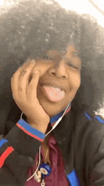 a woman with curly hair is sticking her tongue out and smiling .