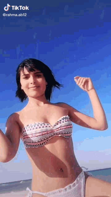 a woman in a bikini is standing on a beach .