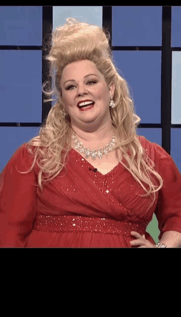 a woman wearing a red dress and a necklace smiles