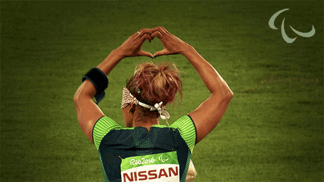 a woman wearing a nissan shirt making a heart shape with her hands
