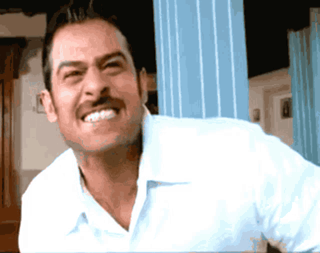 a man with a mustache and a white shirt smiles