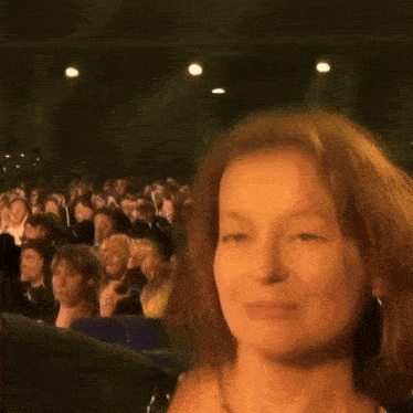 a woman with red hair is sitting in a crowd of people